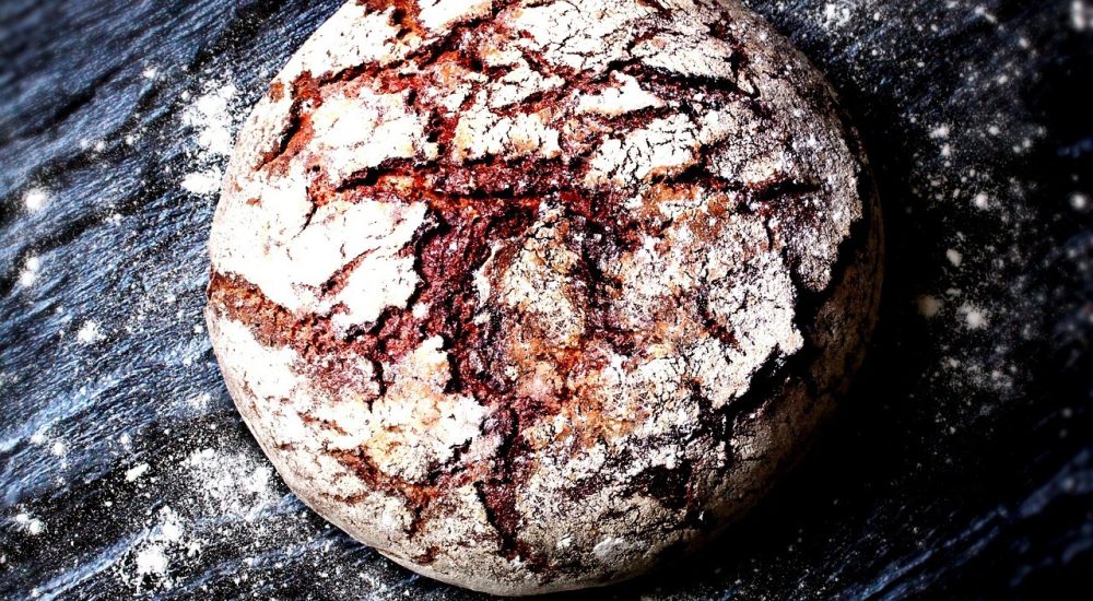 Bild: Brotbackkurs - Ein rundes vollwertiges Vollkornbrot liegt auf einer schwarzen Steinplatte.